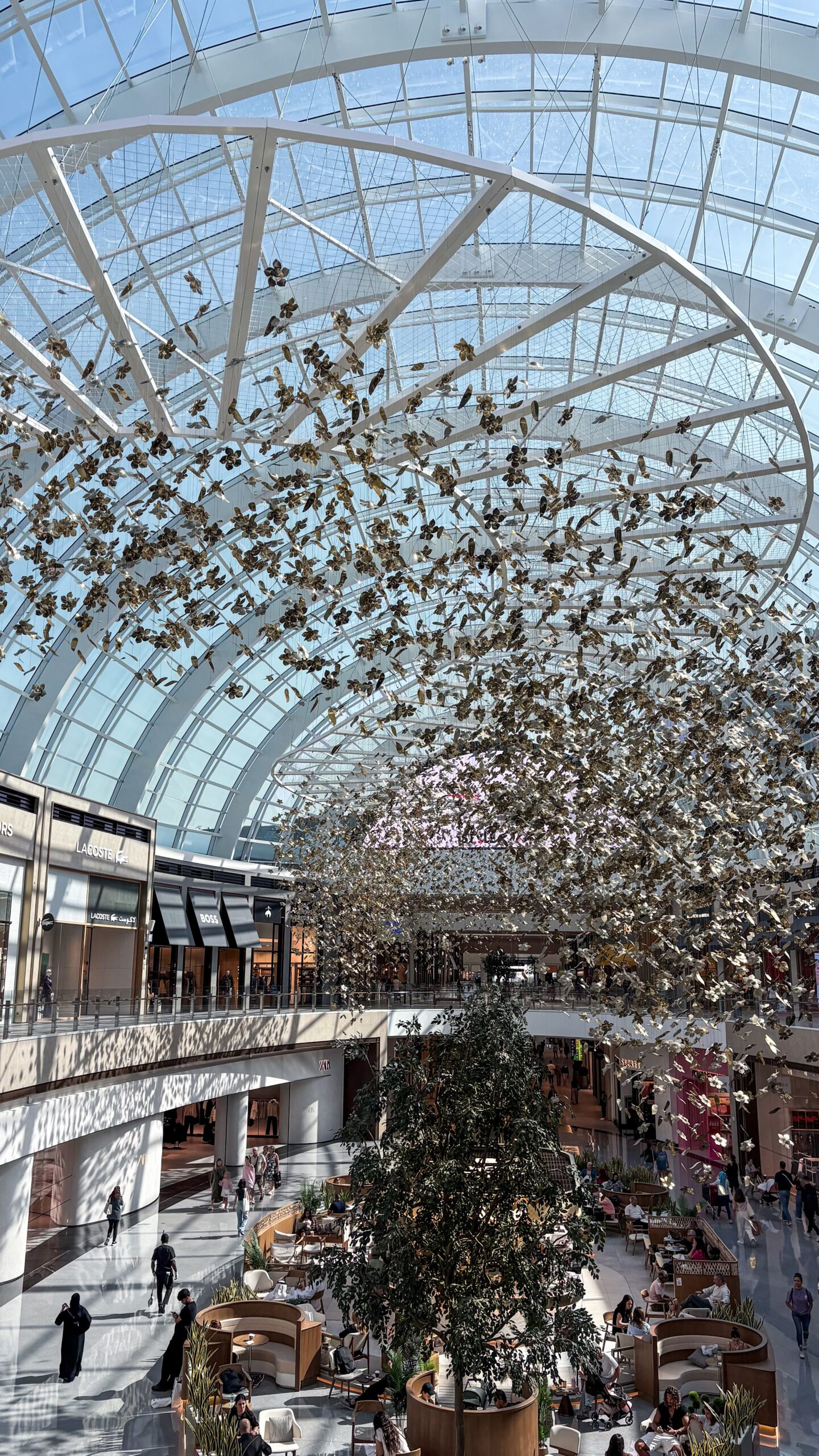 Stunning interior view of a modern mall with a glass ceiling and intricate hanging art.